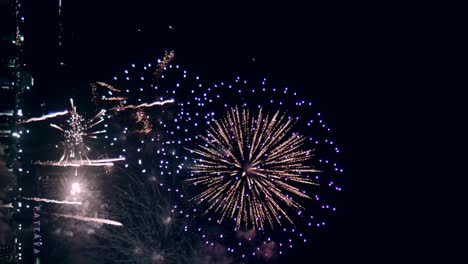 los fuegos artificiales de la víspera de año nuevo exhiben un bucle de celebración sin costuras de fondo de fuegos artificiales reales con un gran espectáculo de fuegos artificiales brillantes multicolores abstractos con luces bokeh en el cielo nocturno