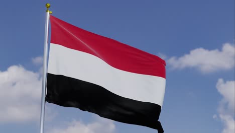 Bandera-De-Yemen-Moviéndose-En-El-Viento-Con-Un-Cielo-Azul-Claro-En-El-Fondo,-Nubes-Moviéndose-Lentamente,-Asta-De-Bandera,-Cámara-Lenta