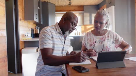 senior african american couple doing paperwork using tablet at home, slow motion
