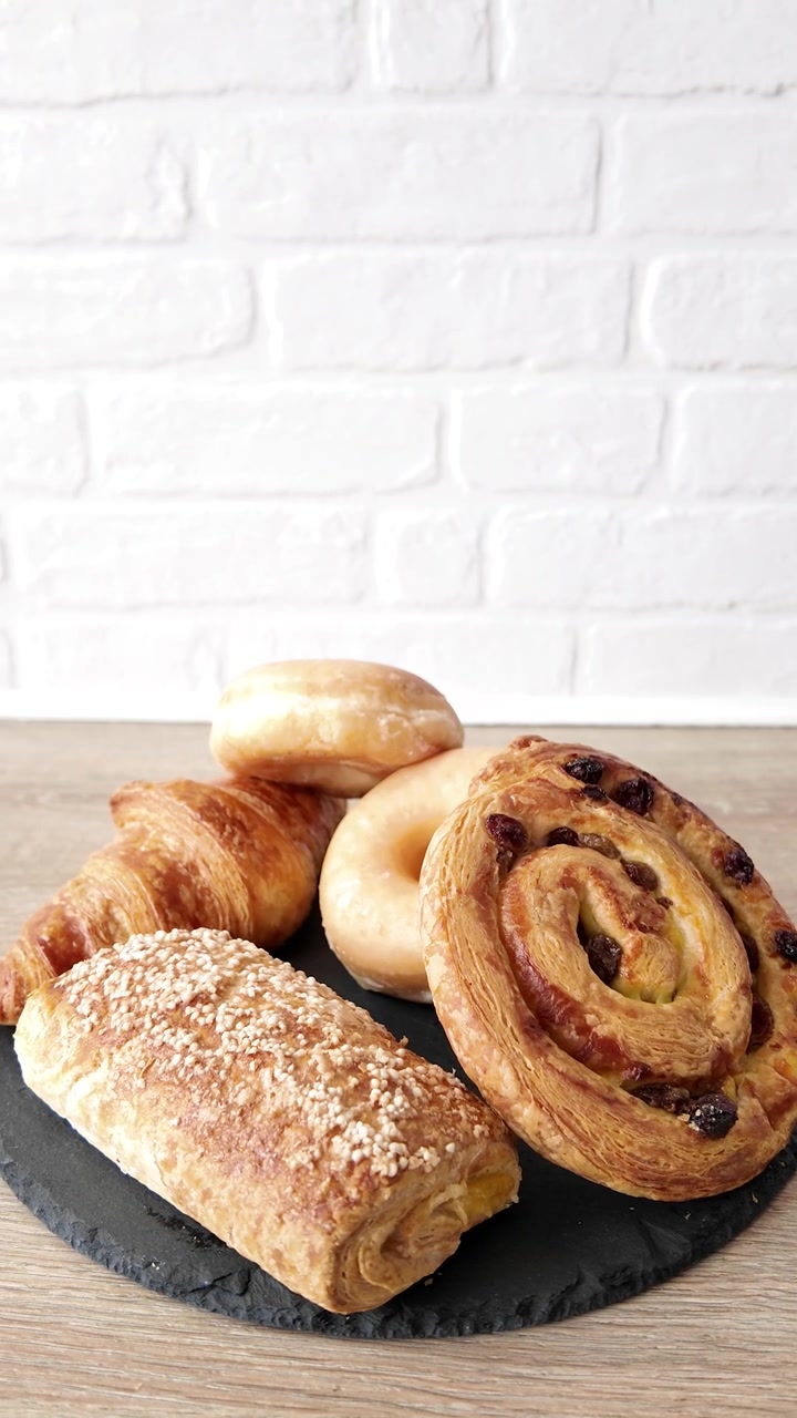 Hand Taking Fresh Croissant from Assorted Breakfast Pastries