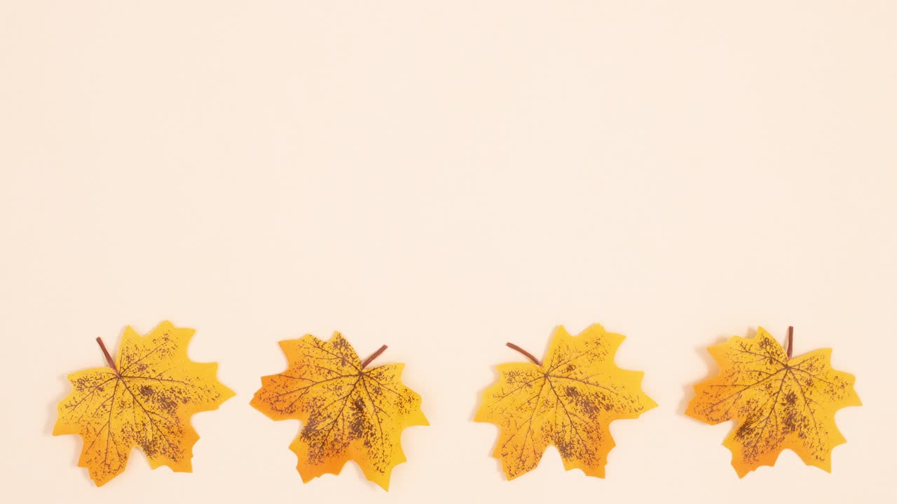 Autumn yellow leaves rotating on bottom of beige background. Stop motion