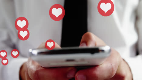 animation of hearts over hands of biracial man using smartphone