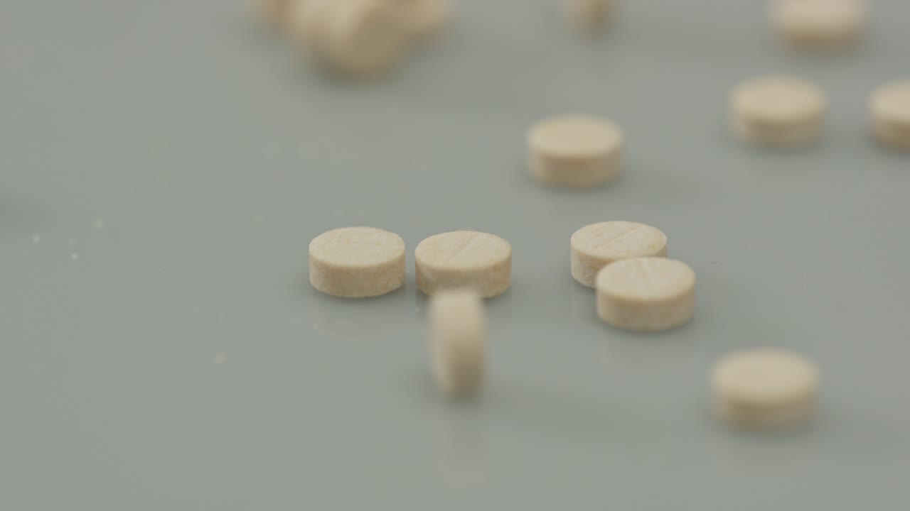 Close-up of Scattered White Pills on a Grey Surface
