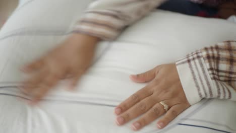 woman fluffing a pillow on her bed