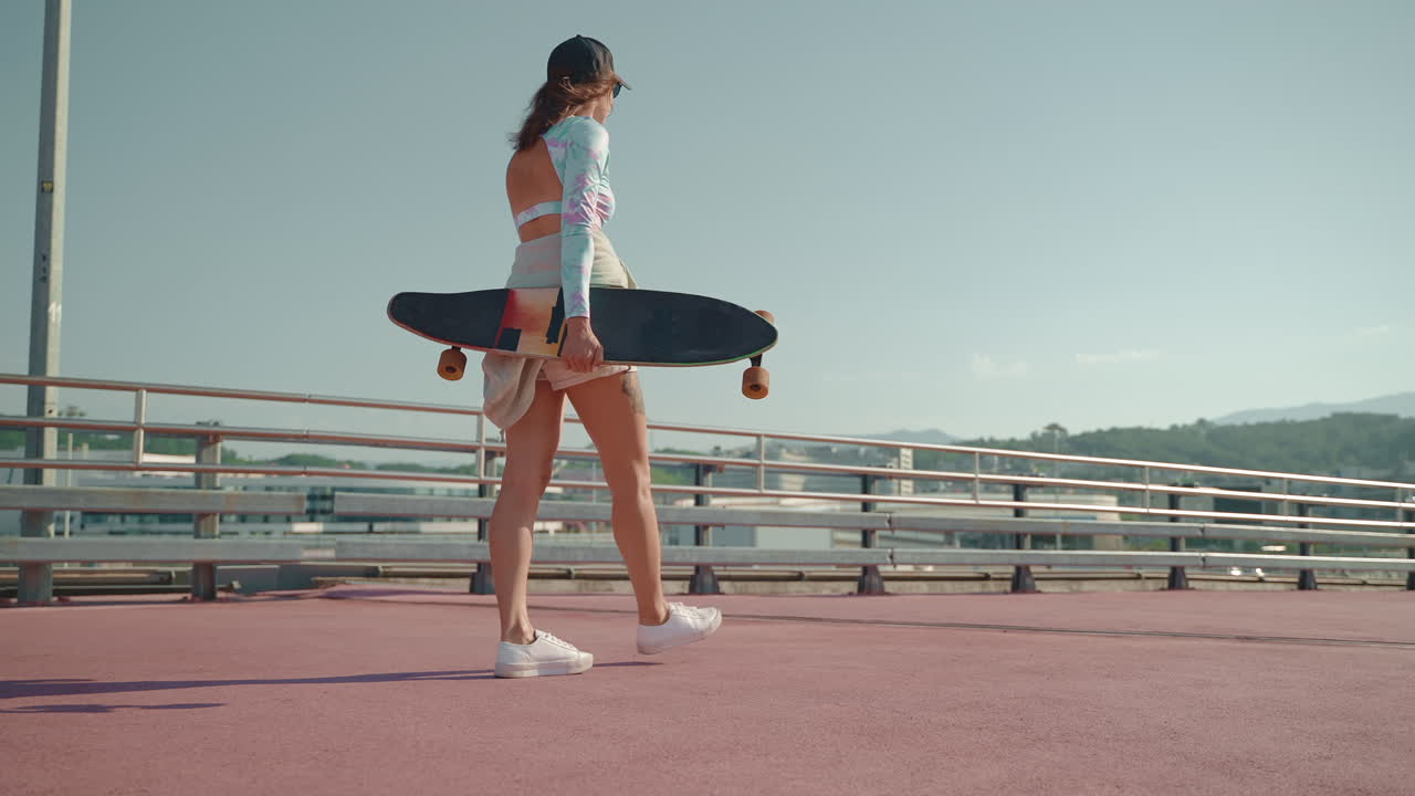 Woman Walking with Longboard on a City Bridge
