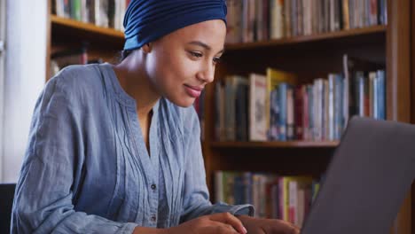 Asian-female-student-wearing-a-blue-hijab-sitting-using-laptop-and-cheering