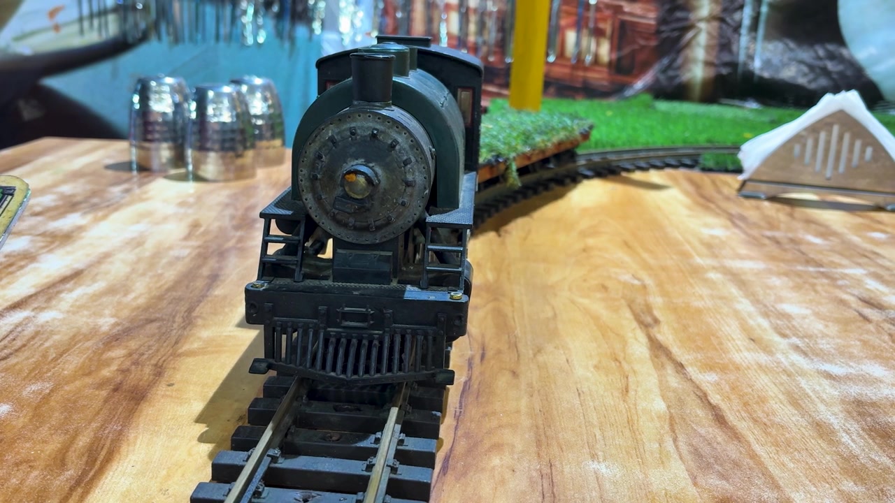 Locomotiva a vapore modello vintage esposta su un binario ferroviario in miniatura all'interno, primo piano