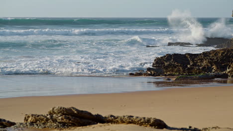 An-Einem-Sonnigen-Tag-Bricht-Das-Meer-An-Einem-Felsigen-Strand.-Weiße,-Schäumende-Wellen-Rollen-An-Der-Küste-Entlang