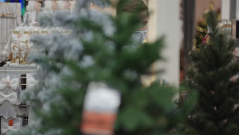 Father-and-daughter-go-to-the-store-and-choose-Christmas-trees-in-protective-masks