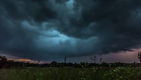 Time-lapse-of-dark-stormy-clouds-flying-over-flower-field-after-sunset-time,4K