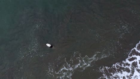 AERIAL:-drone,-surfer-waiting-for-the-waves,-ascending-view