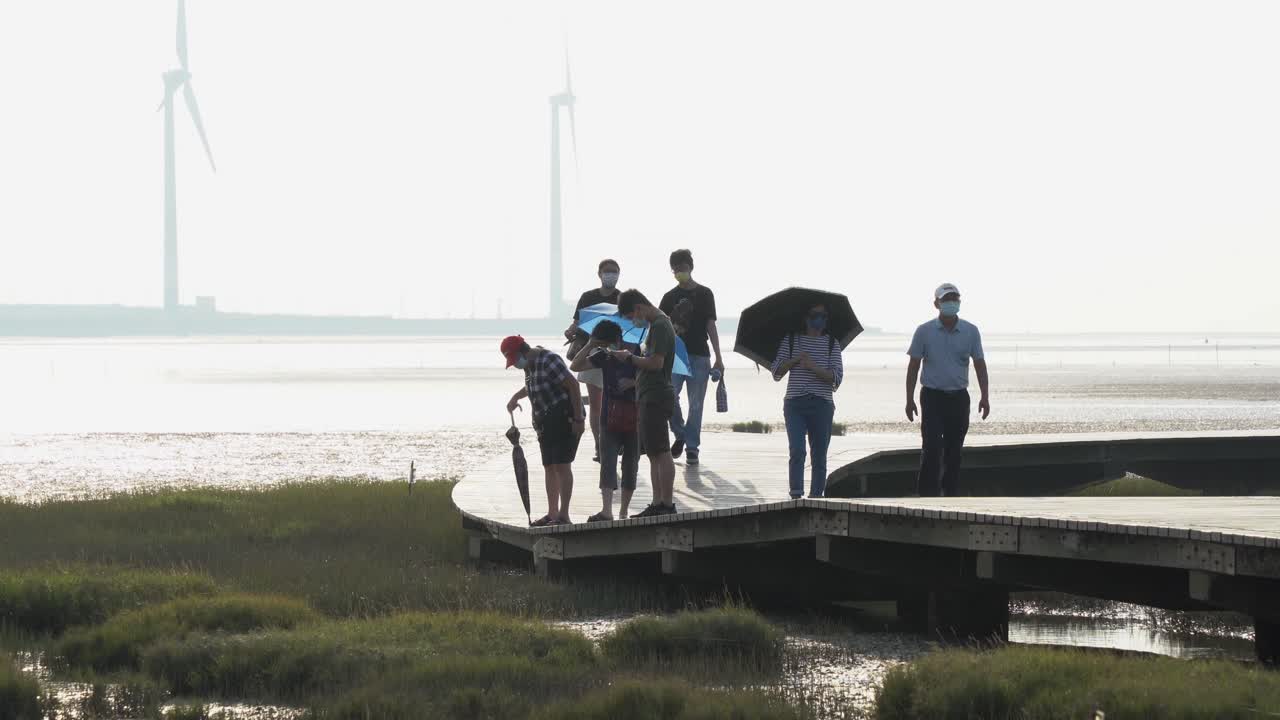 Tourists strolling on the boardwalk observing the wildlife nature Gaomei wetlands preservation area has to offer, beautiful mangrove tidal flat landscape, Taichung, Taiwan.