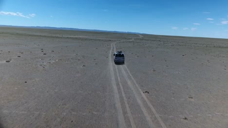 un disparo aéreo de un avión no tripulado siguiendo una furgoneta en el desierto de gobi.