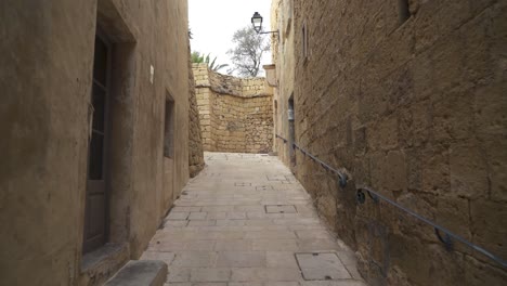 Caminando-Por-La-Estrecha-Calle-Adoquinada-Cittadella-Con-Pasamanos-De-Hierro-En-La-Pared-En-La-Isla-De-Gozo