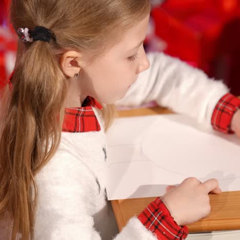 cute child paints a picture with a pen at home. little girl draw a picture for santa in new year in the room. profile view