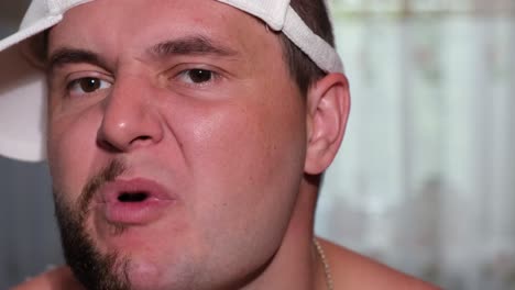 man makes funny facial expressions while shaving his beard