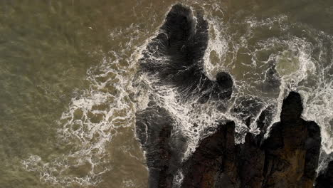 Toma-Aérea-Ascendente,-Olas-En-La-Costa-De-Rocas