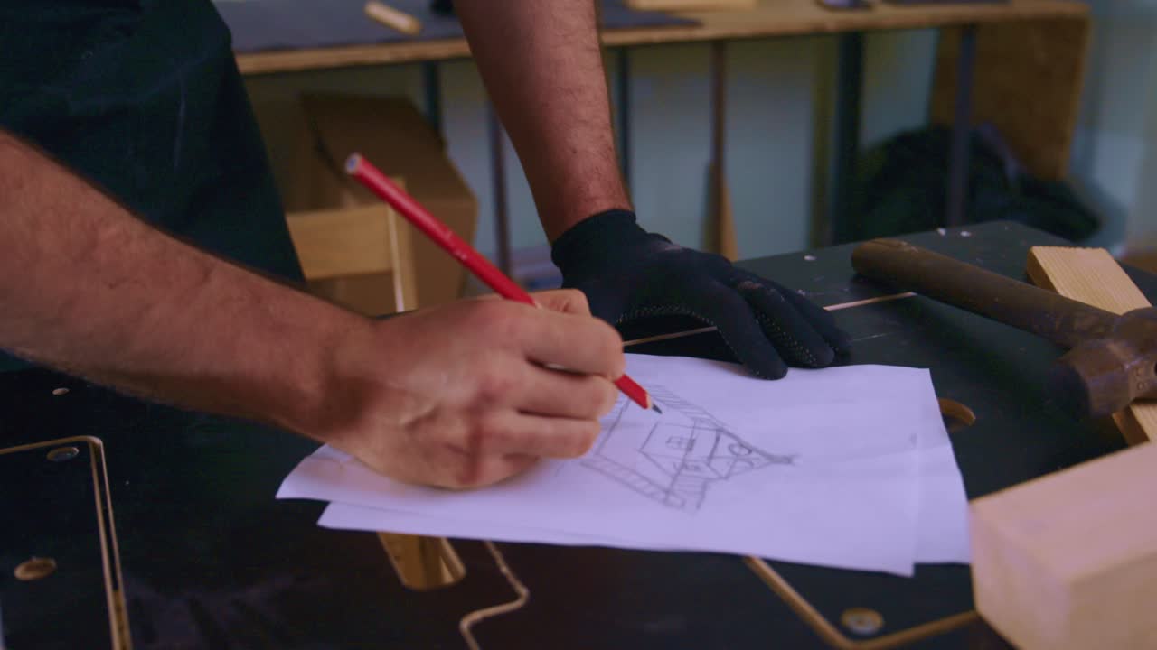 Close Up of Carpenter's Hands Drawing a House Design on Paper