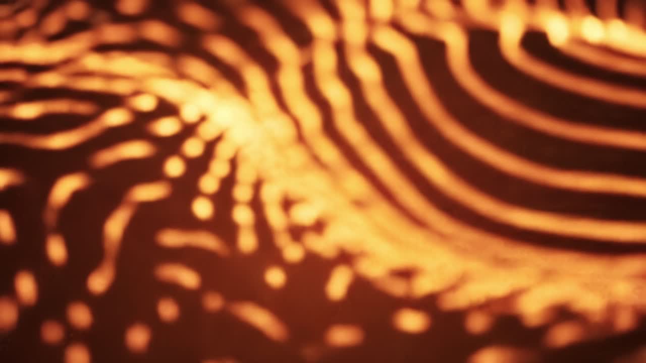 Dynamic waves of orange and yellow light flow across a surface, creating mesmerizing patterns in an urban setting at night. The energetic display captivates viewers with its vibrant colors.