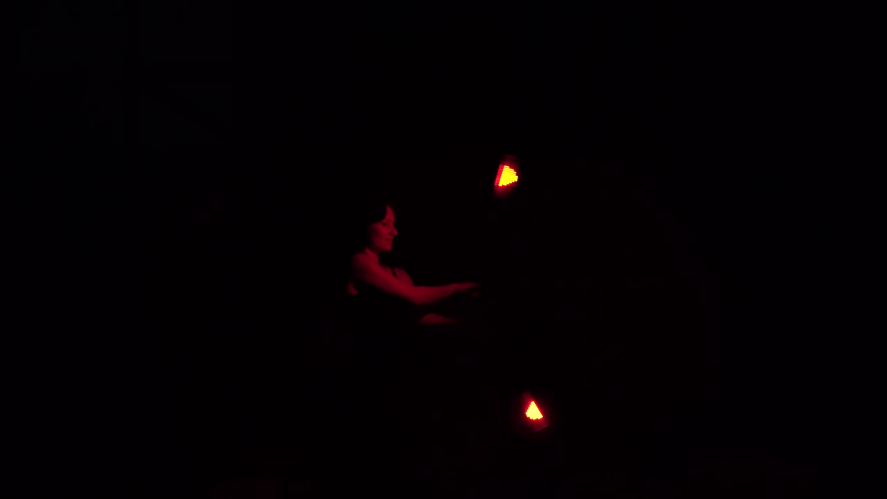 una chica morena en la oscuridad muestra un espectáculo de fuego.