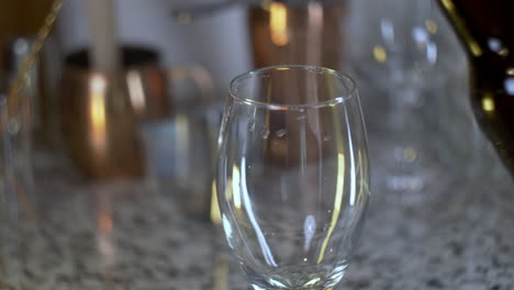 cerveza vertiendo en un vaso de cerveza de una botella marrón en el bar de la casa en cámara lenta