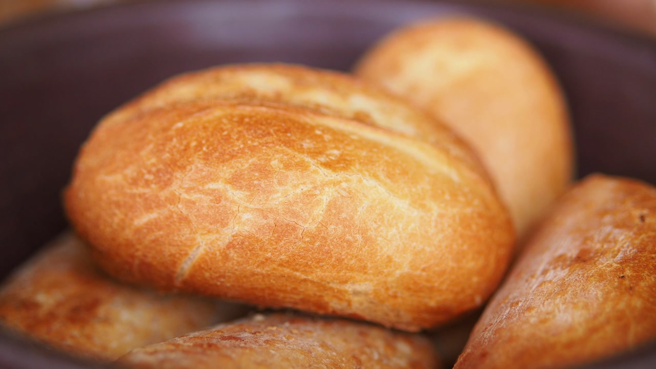 Close-up of a Hand Picking Up a Freshly Baked Bread Roll