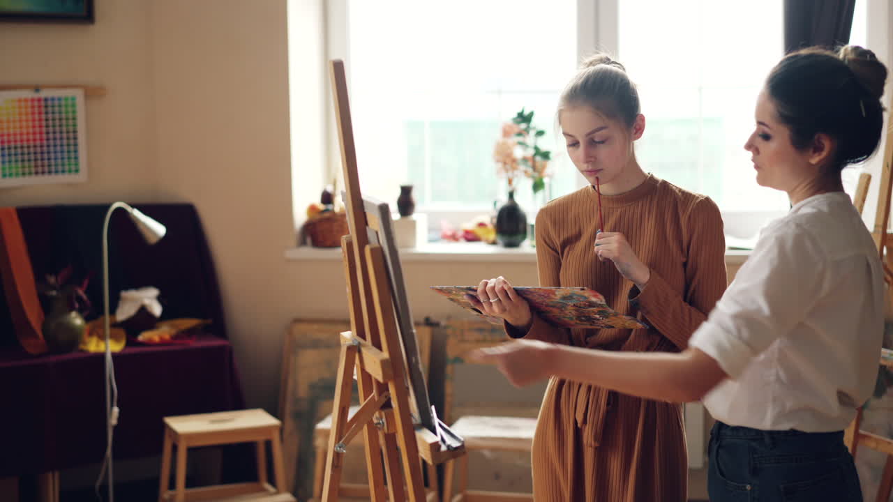 Two women learning painting techniques in an art studio