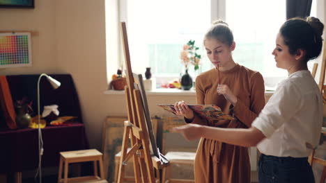 two women learning painting techniques in an art studio