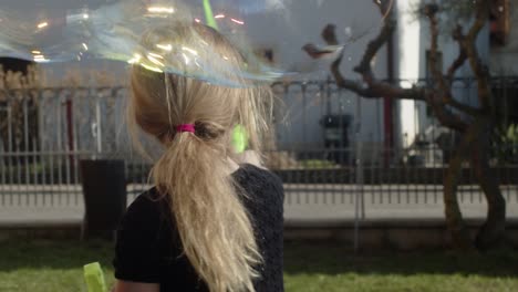 child is playing in park with soap bubbles