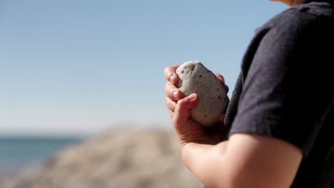 boy holding a rock by the water