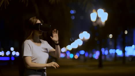 a young girl in virtual reality glasses in a large metropolis simulates work in the program game virtual reality interface. the concept of augmented reality