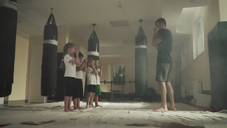 children do blocks with trainer in martial arts school. little boxing students learn self-defence under instructor control in gym slow motion