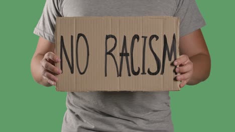 man holds in front of him a poster from a cardboard box with the words no racism. concept of strike and anti racism. isolated a green screen, chroma key. close up. slow motion