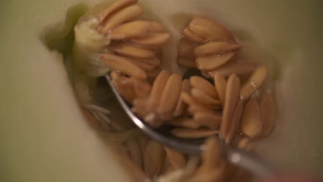 scooping the seeds out of a juicy, ripe honey-dew melon