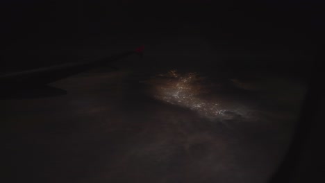 a mesmerizing view from an airplane of glowing city lights nestled amidst the dark andes mountains, cusco, peru - pov