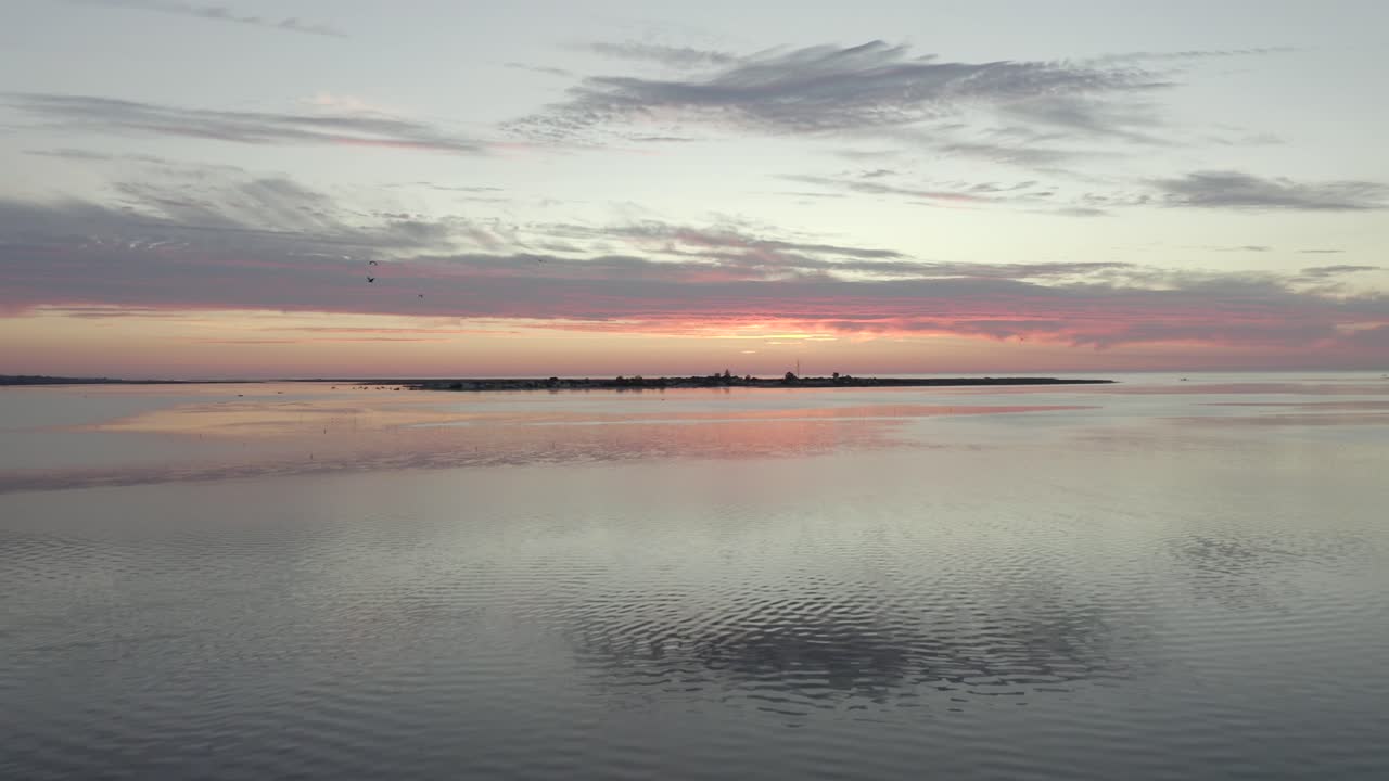 새들이 잔잔한 바다 위로 날아가는 동안 포르투갈 올하우(olhau)의 도시 풍경 위로 아름다운 일출