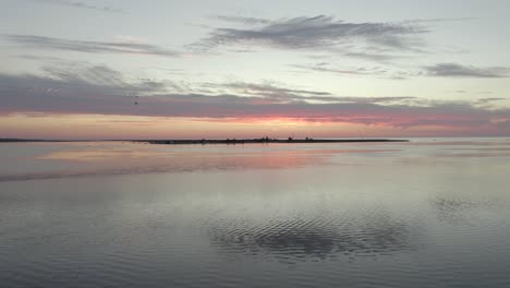 beautiful sunrise over cityscape in olhau, portugal while birds fly over the calm waters