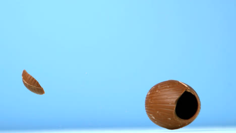 animación de formas caleidoscópicas rojas sobre huevo de pascua de chocolate cayendo y rompiéndose, en azul