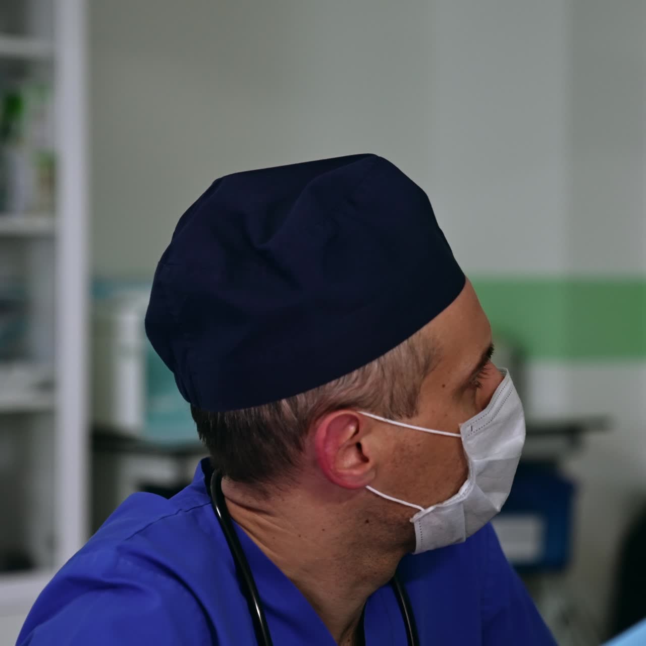 Anesthesiology specialist sitting next to the patient at operation. Doctor is looking attentively at the equipment working in the surgery room
