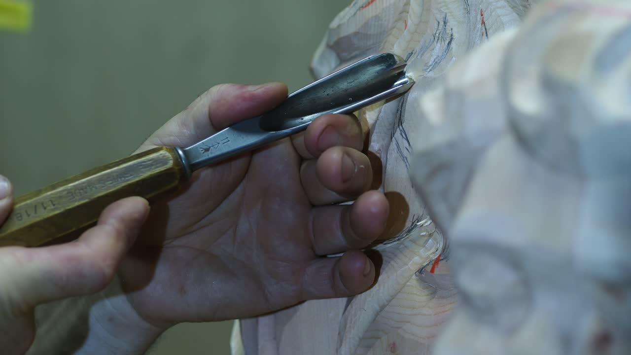 Artisan skillfully carves delicate lines into a wooden sculpture using a sharp chisel, focusing on intricate detail in a traditional workshop setting