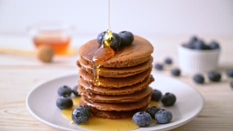 chocolate pancake stack with blueberry and honey on plate