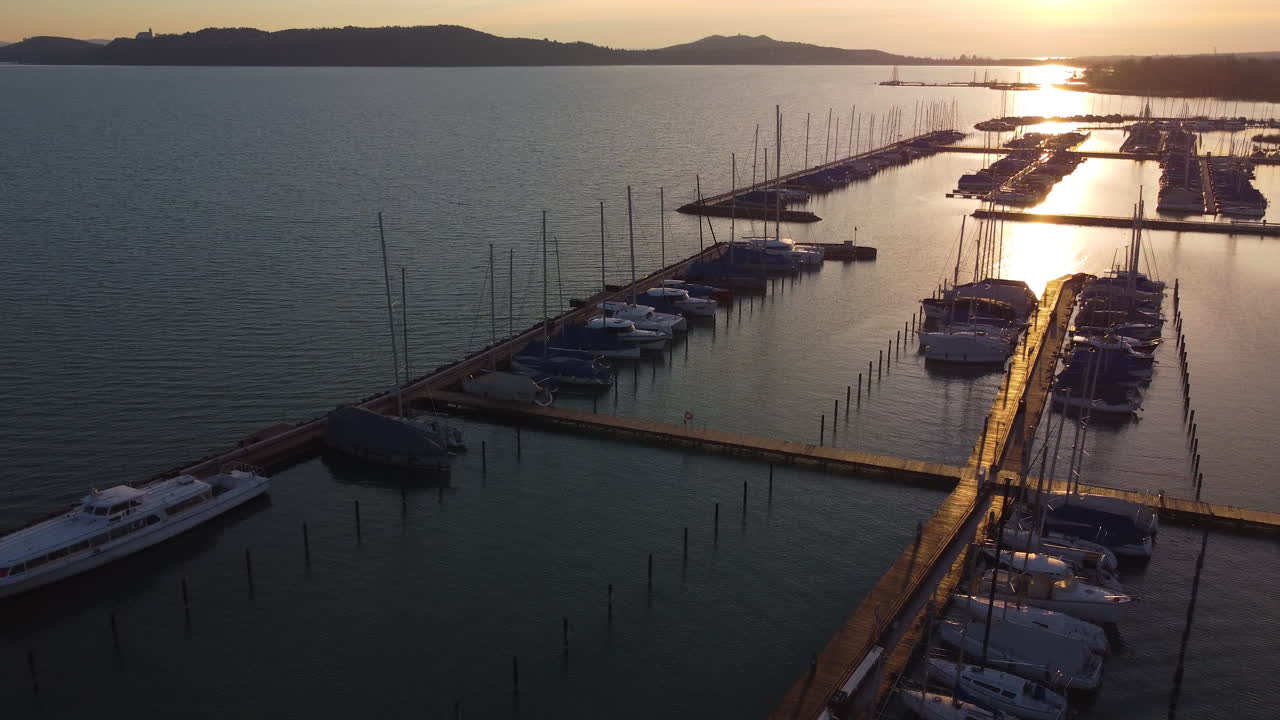 Sunset pier shot at Balatonfured marina with still boats casting shadows on warm water