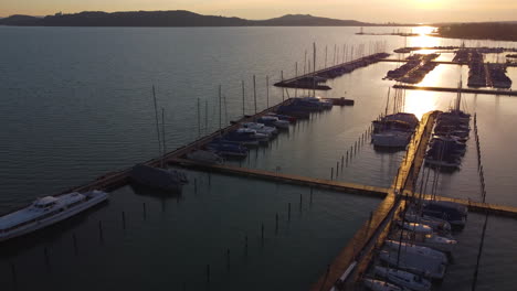 sunset pier shot at balatonfured marina with still boats casting shadows on warm water