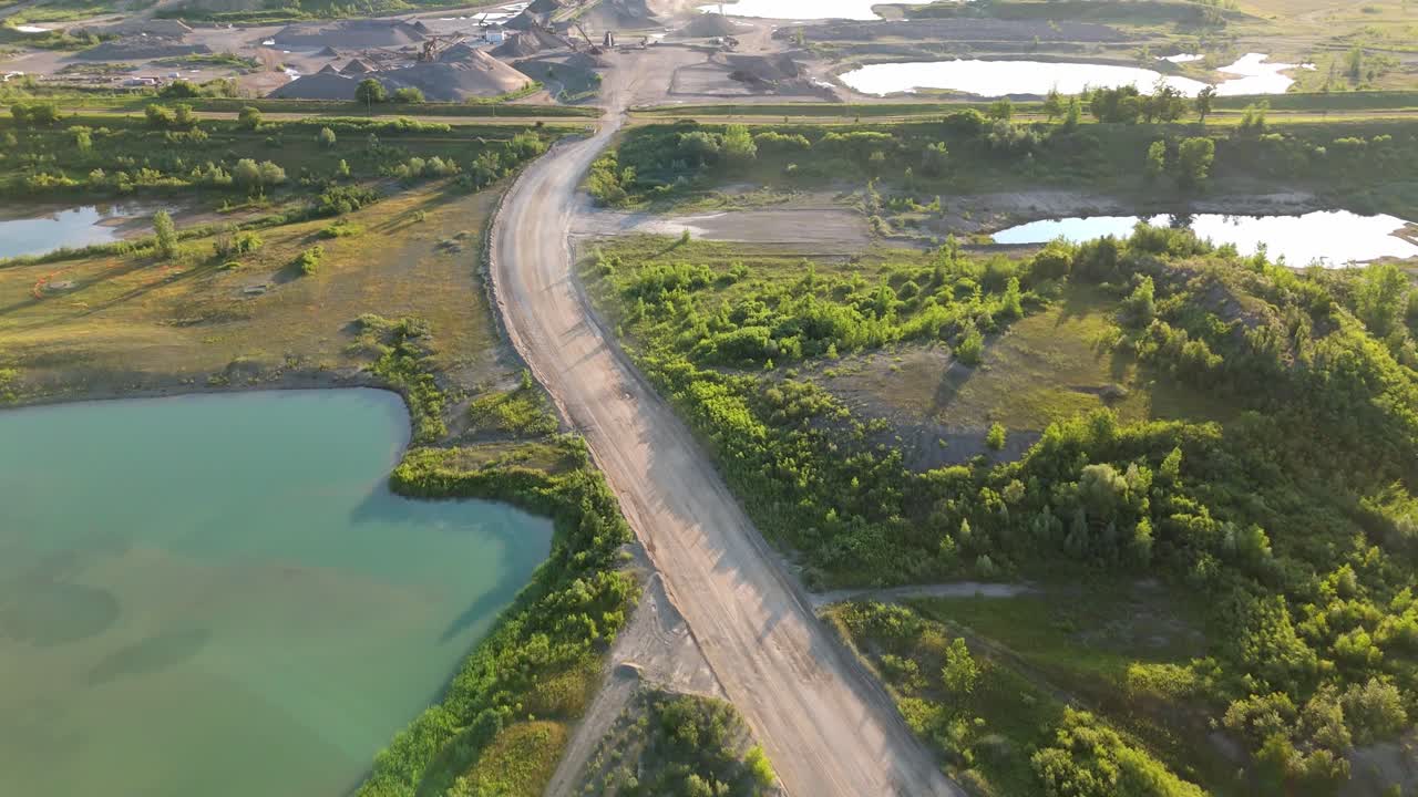 Aerial view of a gravel pit road next to serene lakes, lush greenery