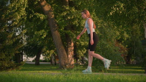 una joven patinando con gracia en un parque al aire libre rodeada de exuberantes árboles naturales, su enfoque y comportamiento relajado se mezclan armoniosamente con la cálida luz del sol que se refleja a través de la vegetación