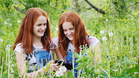 two red-haired twin sisters listen to music on headphones 1