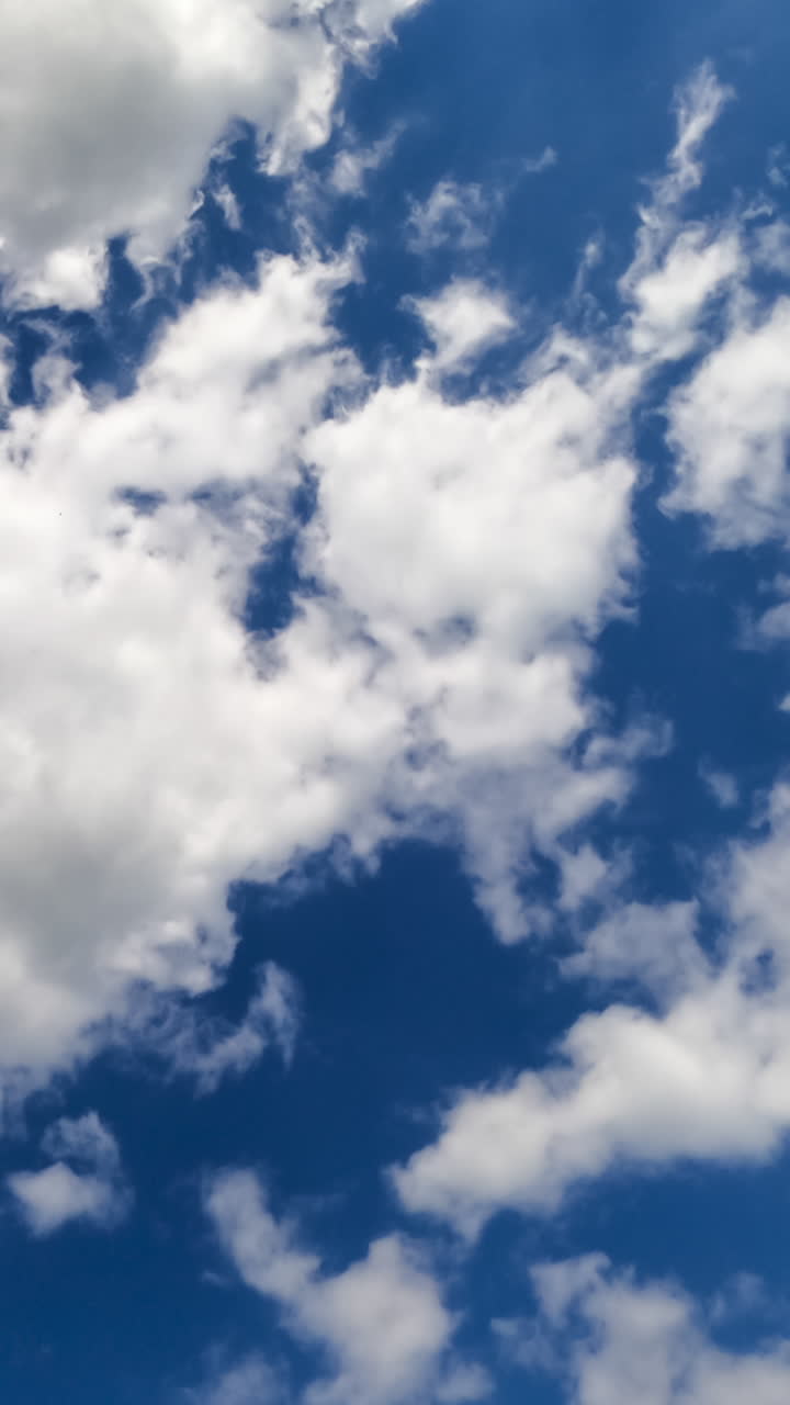 Puffy airy clouds transforming at the wind. Heavenly beautiful blue skies with clouds timelapse. Vertical video