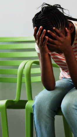 upset girl sitting on chair in hospital corridor