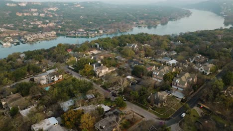 suburban neighborhood homes in tarrytown, austin texas overlooking lake austin aerial pull away and tilt up at sunrise in 4k