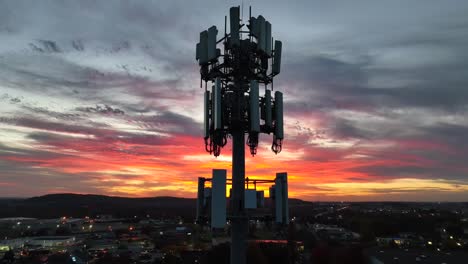 cell phone tower at night against bright sunset sky in america